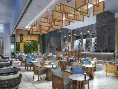 Modern hotel restaurant interior with stylish wooden furniture and hanging lighting.