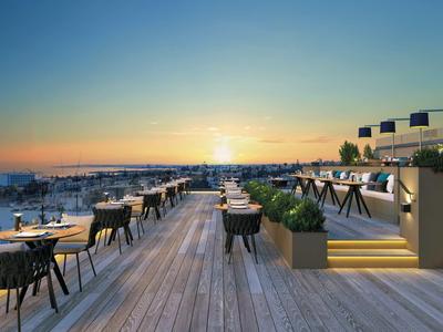 Rooftop terrace with modern seating and sea view at sunset.