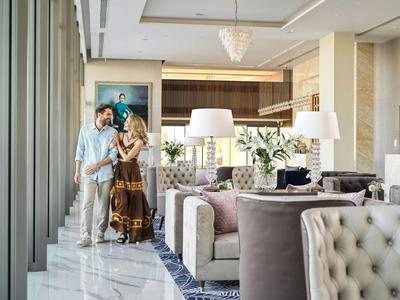 A couple stands in an elegant hotel lounge area with comfortable chairs and modern lighting.