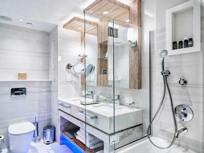 Modernes, helles Badezimmer mit Doppelwaschbecken, großer Glasdusche und weißer Einrichtung.