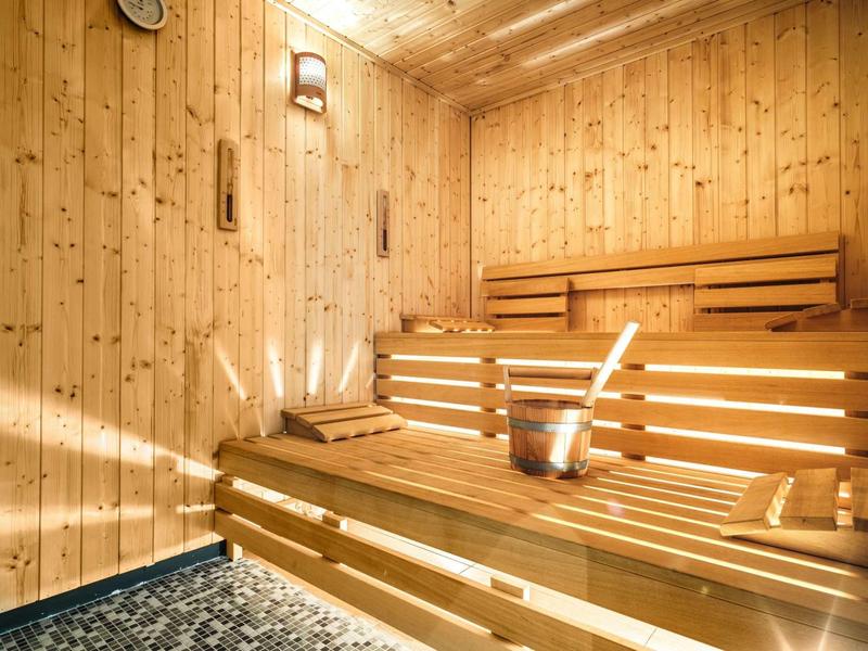 Holzsauna mit Bänken, Eimer, Kelle und Handtüchern, warmes Licht durchflutet den Raum.