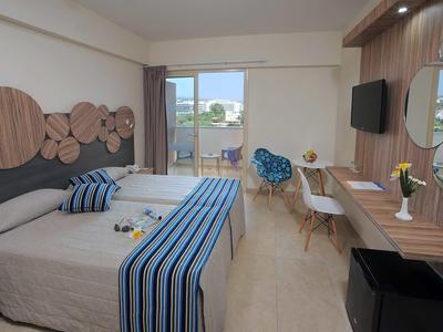 Modernes Hotelzimmer mit zwei Betten, Holzakzenten, Schreibtisch und Balkon mit Blick nach draußen.