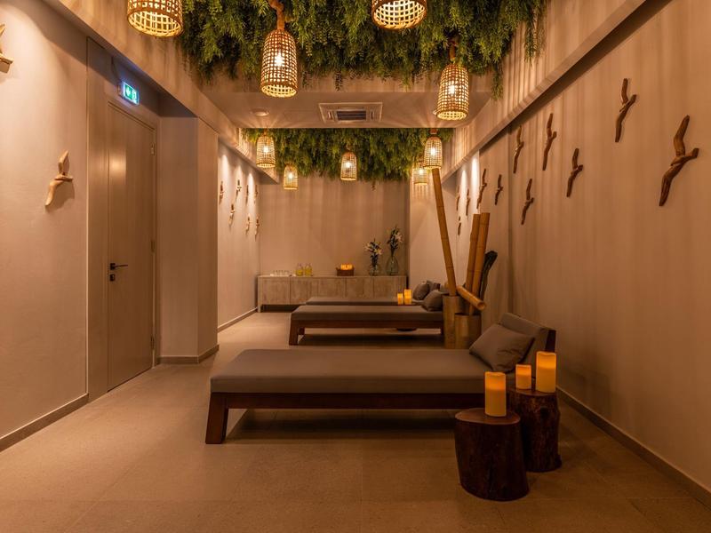 Klidná spa místnost s pohodlnými lehátky, svíčkami a přírodní dekorací na stěnách a stropě.