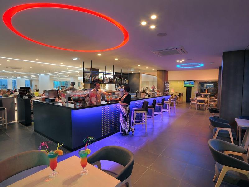 Moderní hotelový bar s osvětleným pultem, sezením a stylovou atmosférou.