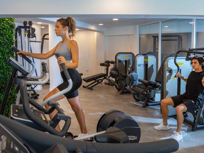 Donna che si allena su uno stepper in una palestra moderna dell'hotel.