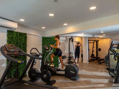 Palestra moderna dell'hotel con varie attrezzature e una persona su una cyclette.