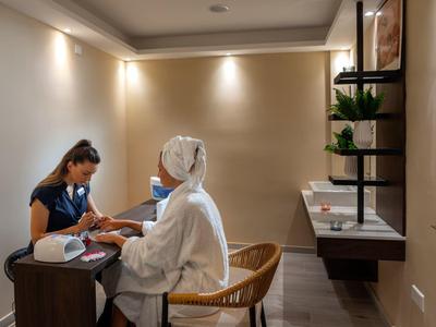 Zwei Frauen sitzen sich in hellem Raum gegenüber, eine misst Blutzucker bei der anderen.