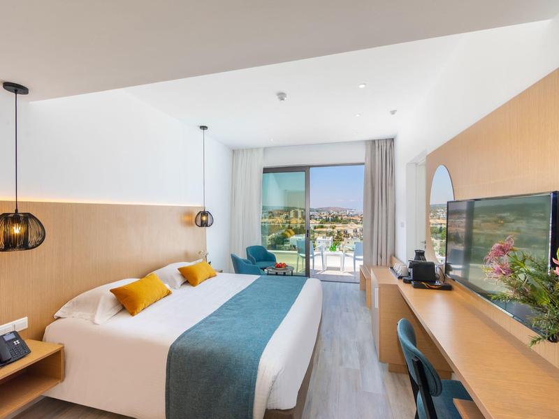 Modernes Hotelzimmer mit zwei Betten, großem Fenster, Holzmöbeln und blau-weißer Bettwäsche.