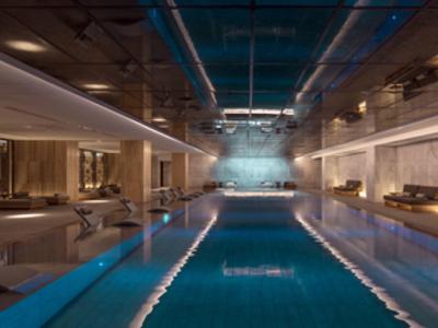 Moderner Innenpool mit blauer Beleuchtung, hohen Decken und stilvollen Holzmöbeln rechts und links.