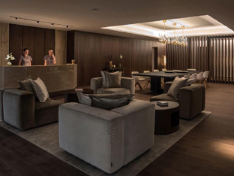 Elegantes, gedämpft beleuchtetes Wohnzimmer mit grauen Polstermöbeln und dunklem Holzboden.