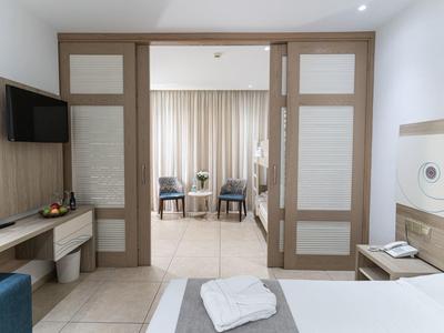 View of a hotel room with open sliding doors leading to a living area with curtains.