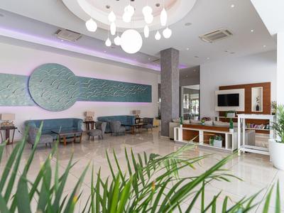 Heller Hotel-Loungebereich mit modernen Möbeln und grünen Pflanzen.