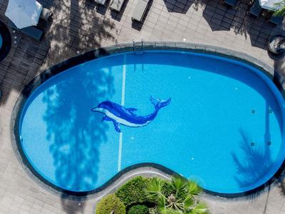 Blick auf einen geschwungenen Hotelpool mit einem blauen Delfin-aufblasbaren Spielzeug.