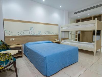 Modern eingerichtetes Hotelzimmer mit Doppelbett und Etagenbett in neutralen Farben.