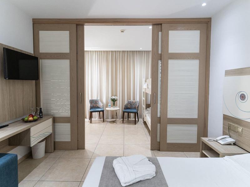 View of a hotel room with open sliding doors leading to a living area with curtains.