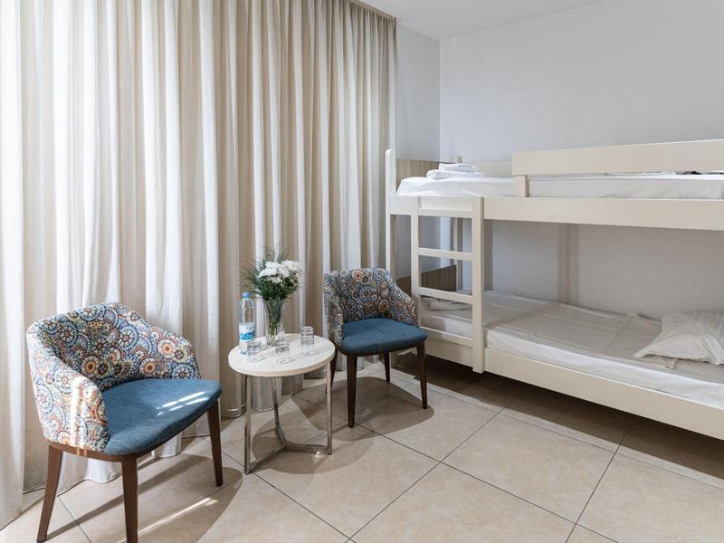 Bright room with bunk bed, two chairs, and a small round table.