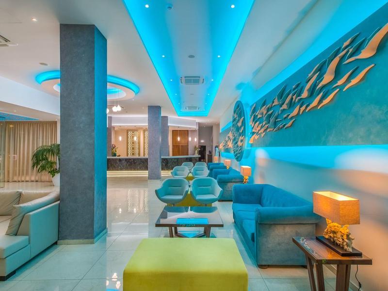 Modern hotel lobby with blue walls, seating areas, and stylish lighting.