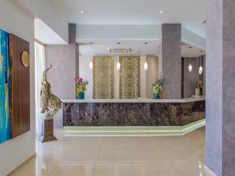 Modern hotel lobby reception area with front desk, floral decorations, and wall art.