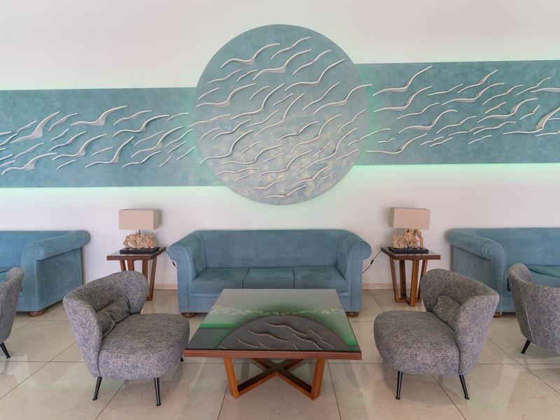 Modern hotel lounge with blue sofas, gray armchairs, and blue-gray wall art.