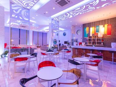 Modern eingerichteter Gastraum mit farbigen Stühlen und indirekter Beleuchtung.