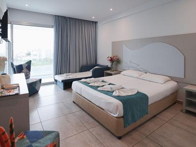 Nowoczesny pokój hotelowy z łóżkiem podwójnym, leżanką, biurkiem i dużym oknem z widokiem.