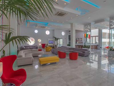 Helles, modernes Wohnzimmer mit grauer Couch, roten Hockern, gelbem Tisch und großen Fensterfronten.