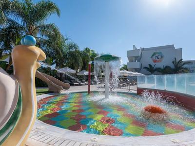Bunter Kinderspielplatz mit Wasserspielen, Palmen und Rutschen bei sonnigem Himmel.
