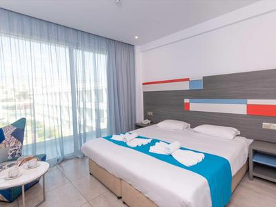 Modernes Hotelzimmer mit Doppelbett, modernen Möbeln und großen Fenstern mit Vorhängen.