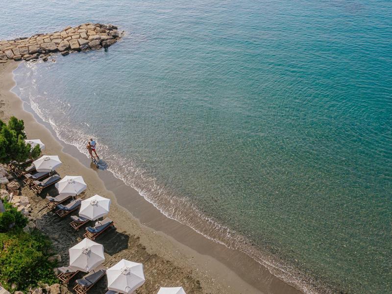 A quiet beach with sun loungers and umbrellas by the clear sea.