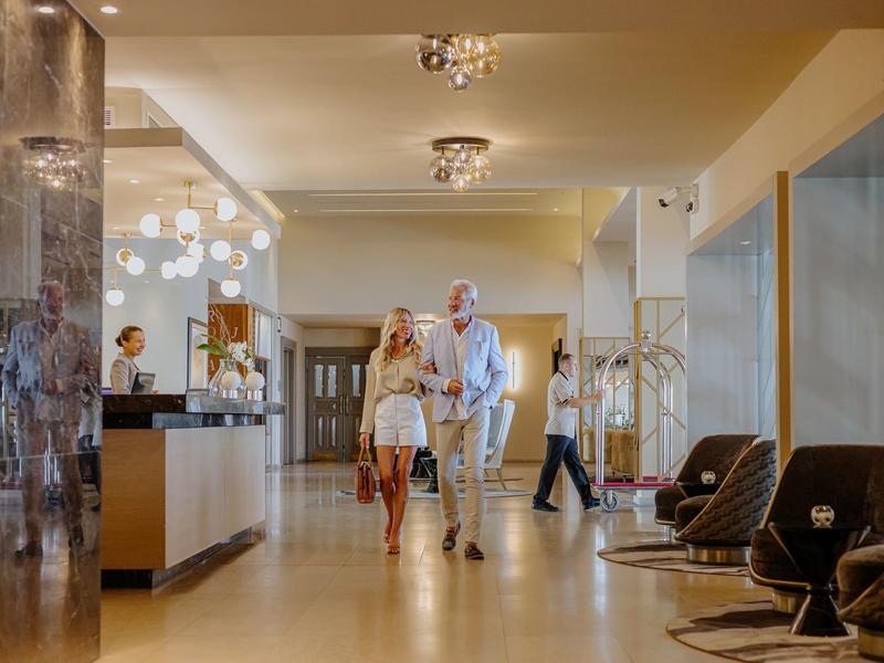 A couple walks through an elegant hotel lobby with modern decor.