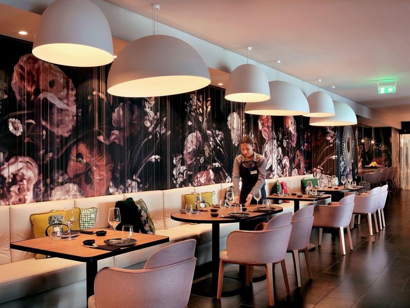 Elegant restaurant with modern design, pink chairs, and large white hanging lamps.