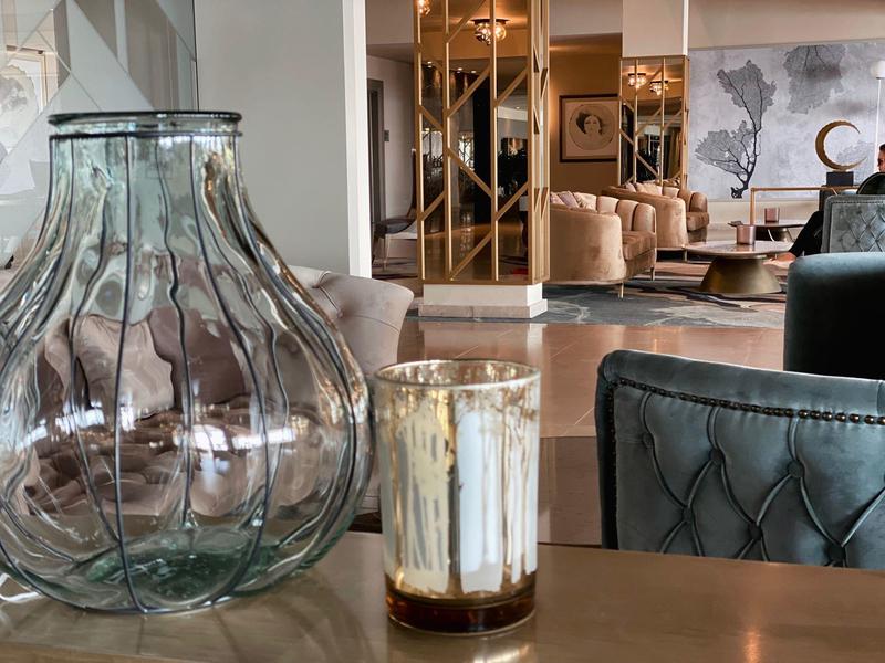 Large glass vase beside a modern sofa in a stylish hotel room.