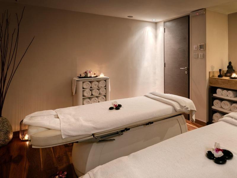 Cozy spa room with two massage tables, warm lighting, and decorative elements.