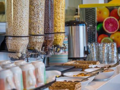 Buffet per la colazione con dispenser di cereali, caffè, biscotti e yogurt in hotel.
