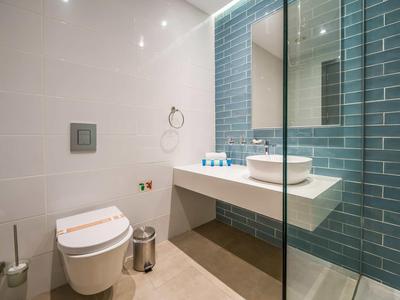 Moderne Badezimmer mit weißer Toilette, Waschbecken auf Platte und blauer Kachelwand.