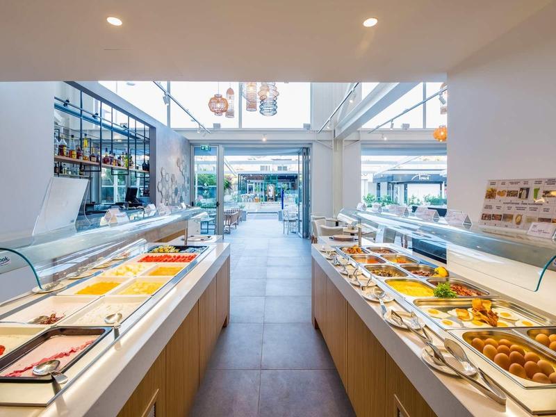 Moderne Buffetreihe mit warmen und kalten Speisen in hellem, geräumigem Restaurant mit Glasfront.