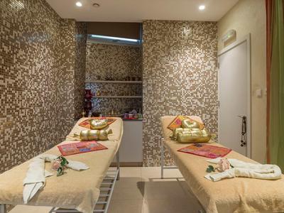 Spokojny pokój spa z dwoma stołami do masażu, ozdobiony ręcznikami i płatkami kwiatów.