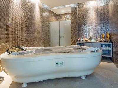 Nowoczesny pokój spa z luksusową wanną do masażu i elegancką mozaikową ścianą.