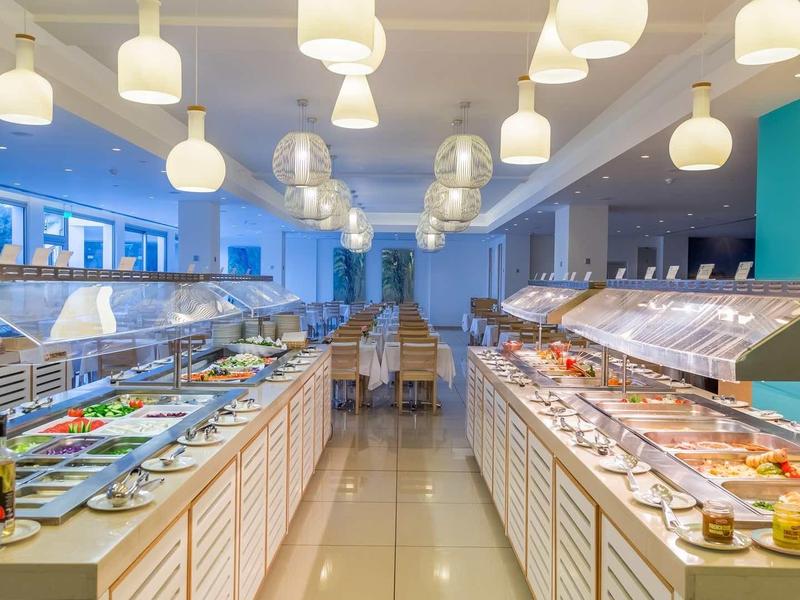 Przestronny bufet z różnorodnymi potrawami pod nowoczesnymi lampami wiszącymi w restauracji.