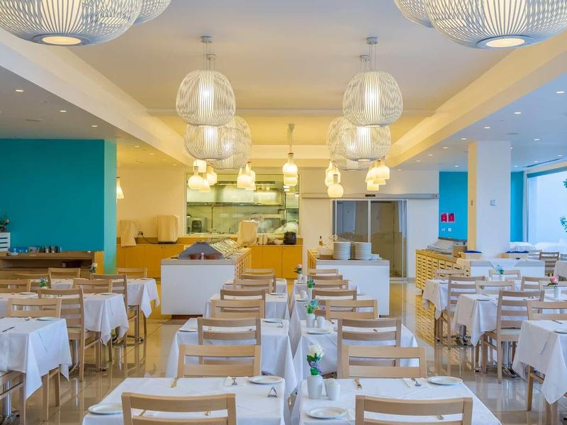 Nowoczesna, jasna restauracja z białymi stolikami i drewnianymi krzesłami w hotelu.