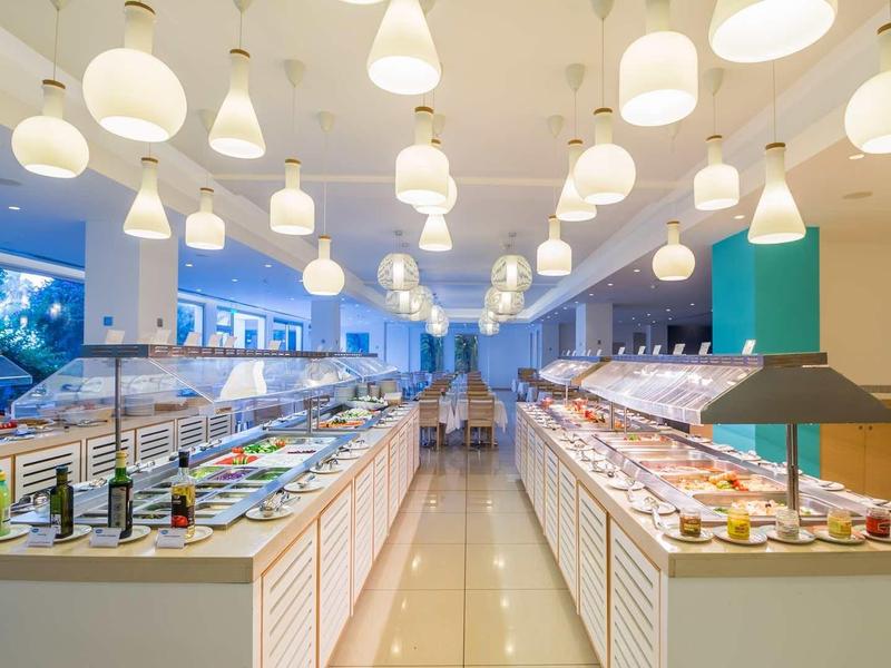 Strefa bufetu w nowoczesnej restauracji hotelowej z różnymi potrawami i stylowymi lampami wiszącymi.