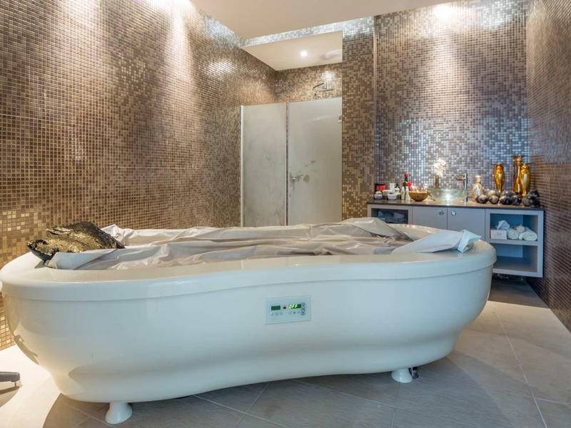 Nowoczesny pokój spa z luksusową wanną do masażu i elegancką mozaikową ścianą.