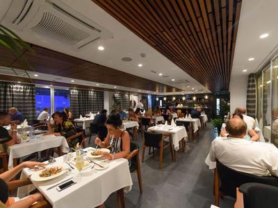 Innenansicht eines gut besuchten Restaurants mit gedeckten Tischen und Gästen beim Essen.