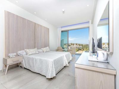 Lichte hotelkamer met tweepersoonsbed, bureau en groot raam met uitzicht.