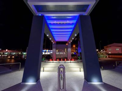 Moderner Hoteleingang bei Nacht mit blauer LED-Beleuchtung und Säulen.