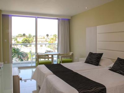 Moderne hotelkamer met tweepersoonsbed, balkon en uitzicht op palmbomen en water