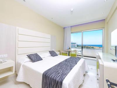 Hotelzimmer mit Doppelbett, Schreibtisch und Balkon mit Meerblick.