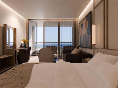 Modernes Hotelzimmer mit Bett, Sitzbereich und Blick auf einen Balkon mit Meerblick.
