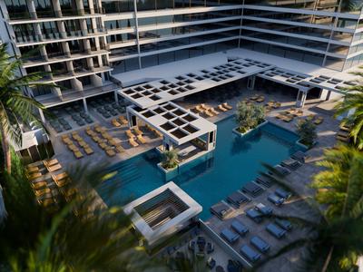 Moderner Hotelpoolbereich mit Sonnenliegen und umliegenden Gebäuden unter Palmen.