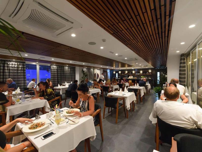 Elegant restaurant met witte tafelkleden en gasten die 's avonds dineren.